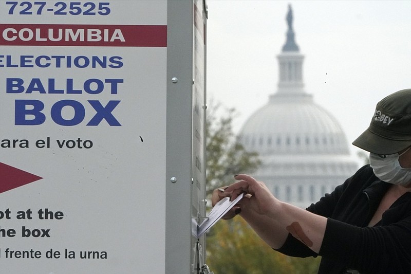 With the U.S. Capitol dome visible, a voter drops a ballot into an early voting drop box, Wednesday, Oct. 28, 2020, at Union Market in Washington. (AP Photo/Patrick Semansky)


