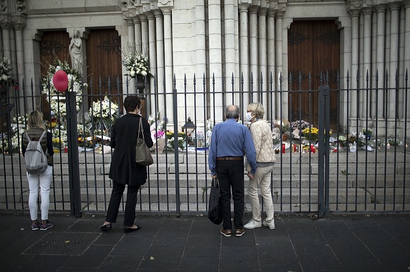 People pay respect to the victims in front of the Notre Dame church in Nice, France, Friday, Oct. 30, 2020. A new suspect is in custody in the investigation into a gruesome attack by a Tunisian man who killed three people in a French church. France heightened its security alert amid religious and geopolitical tensions around cartoons mocking the Muslim prophet. (AP Photo/Daniel Cole)


