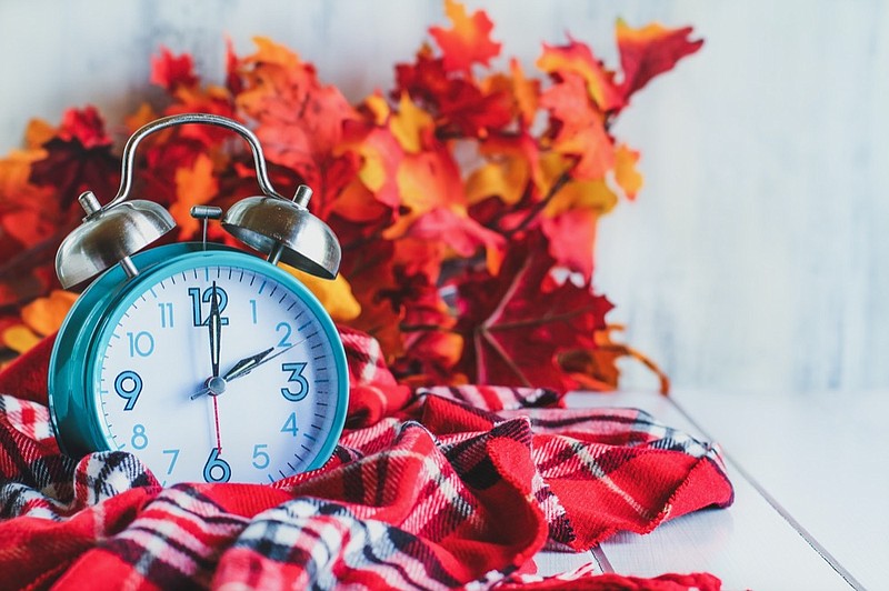 Daylight savings time concept. Set your clocks back with this retro beautiful alarm clocks set to 2 am over rustic white background with red plaid scarf and autumn leaves. Free space for text. fall back tile clock tile time change / Getty Images
