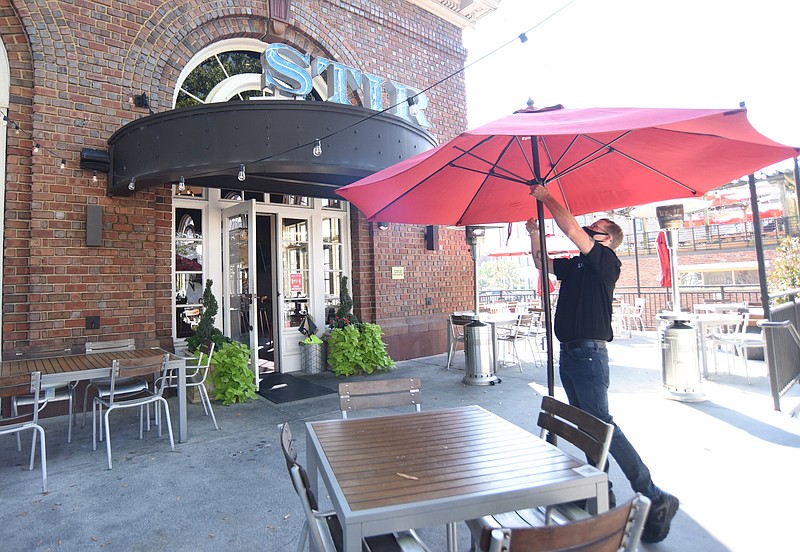 Staff Photo by Matt Hamilton / Server Grant Mitchell opens umbrellas in the outdoor seating area at Stir restaurant on Tuesday, Oct. 6, 2020.