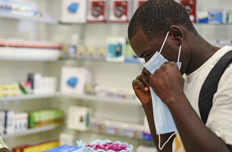 FILE — In this Feb. 6, 2020, file photo, a man tries on a face mask at a pharmacy in Kitwe, Zambia. Facing financial difficulties aggravated by the coronavirus pandemic, the southern African nation of Zambia seems to be headed for a default on debt owed to private investors. (AP Photo/Emmanuel Mwiche, File)