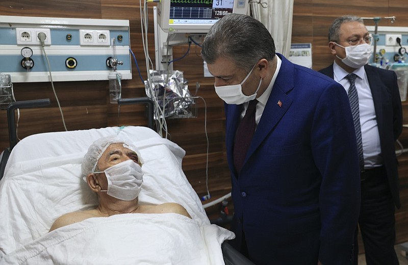 Turkey's Health Minister Fahrettin Koca speaks with Ahmet Citim, rescued from the debris of his collapsed house, in Izmir, Turkey, Sunday, Nov. 1, 2020. In the latest of series of remarkable rescues after the Friday afternoon earthquake, rescue workers extricated the 70-year-old man from the collapsed building earlier on Sunday, some 34 hours after the strong earthquake in the Aegean Sea struck Turkey and Greece, killing dozens of people and injuring scores of others(Turkey Health Ministry via AP)