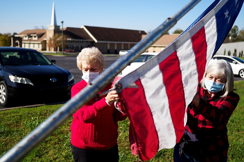Staff photo by C.B. Schmelter / Trinka Rickett, left, and Theresa McKamey raise an American flag for Rickett's father at Ringgold United Methodist Church on Wednesday, Nov. 4, 2020 in Ringgold, Ga. The Ringgold community put up 1,785 flags to honor local veterans. The flags will stay up until Nov. 18.