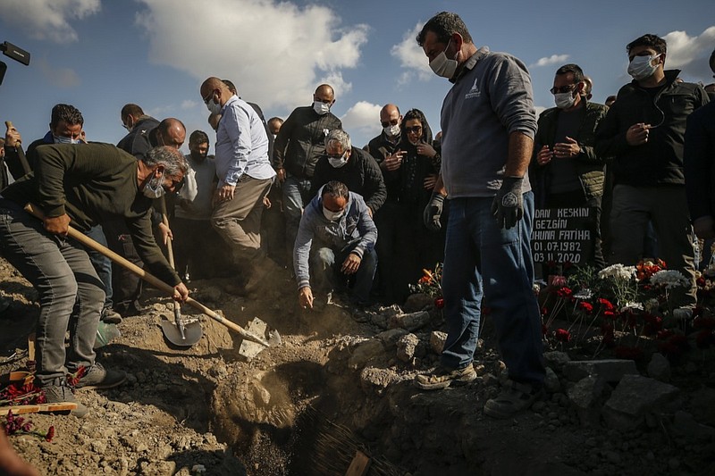 Mourner cover the grave of Fidan Gezgin, killed at her house when it collapsed during the Oct. 30 earthquake, during the funeral procession in Izmir, Turkey, Wednesday, Nov. 4, 2020. Fidan was the mother of Ayda Gezgin who was pulled alive from the rubble of the same building by rescue services Tuesday, some four days (91 hours) after the strong earthquake hit Turkey and Greece. (AP Photo/Emrah Gurel)