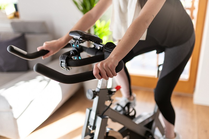 Low section shot of a woman in sportswear exercising on an exercise bike at home. / Photo credit: Getty Images/iStockphoto/SimonSkafar