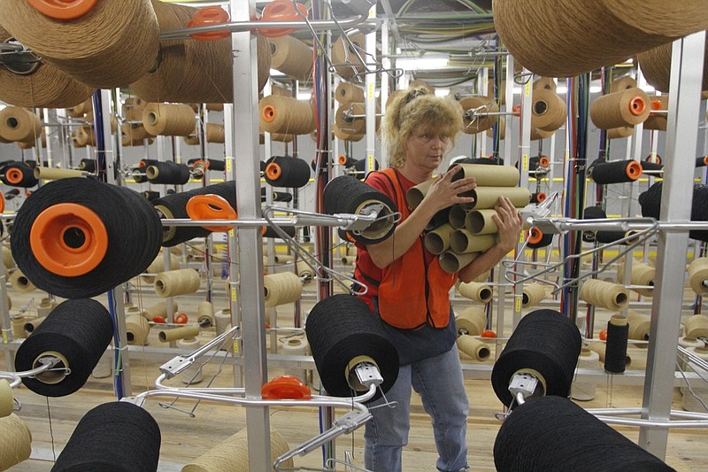 Staff photo by Jake Daniels/Chattanooga Times Free Press 
Donna Shook removes used spools of thread from the creeling area on Friday morning. Workers at the Dixie Group carpet plant in Eton, Georgia, produced, inspected and shipped carpet on Friday. The plant has been surviving in the harsh economic times and Dixie CEO Dan Frierson believes the facility has a bright future ahead.