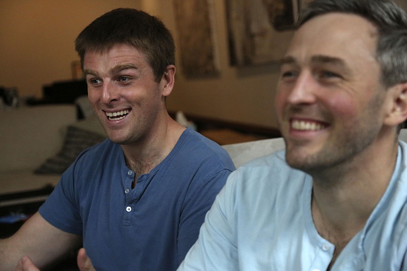 Brothers, Bryan, left, and Bradford Manning, laugh as they tell the origin story of their clothing company, Two Blind Brothers, in their New York City loft on Friday, Oct. 23, 2020. The brothers who've lost much of their vision to a rare degenerative eye disorder began their company in 2016 and have donated all of their profits, more than $700,000, to preclinical research trials to help cure blindness. (AP Photo/Jessie Wardarski)