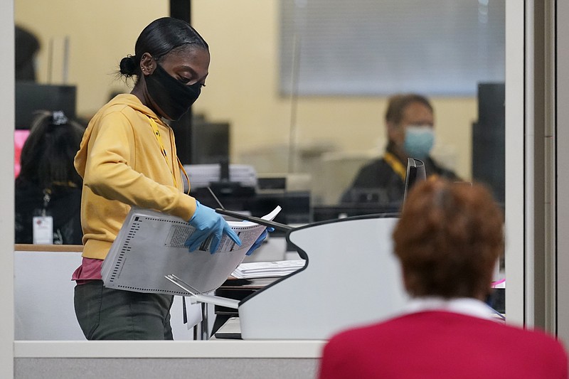 A county election worker scans mail-in ballots at a tabulating area as an observer watches at the Clark County Election Department, Thursday, Nov. 5, 2020, in Las Vegas. Election officials in key battleground states pushed back on claims by the Trump campaign that Republican poll watchers were being improperly denied access to observe the counting of ballots, saying Thursday that rules were being followed and they were committed to transparency. (AP Photo/John Locher)