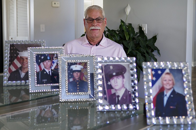 Staff photo by C.B. Schmelter / Veteran Don Raymond poses with military portraits of his family, including his from 1984, left, two of his nephews, his brother-in-law and his niece, at his mother's home on Friday, Nov. 6, 2020 in Soddy-Daisy, Tenn.
