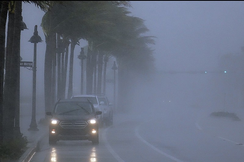 Cars move along highway A1A with poor visability in Fort Lauderdale, Fla., Sunday, Nov. 8, 2020. A strengthening Tropical Storm Eta sliced across Cuba on Sunday and was aimed at the southern tip of Florida, where officials braced for a storm that could hit at hurricane force after leaving scores of dead and over 100 missing in Mexico and Central America. (Joe Cavaretta/South Florida Sun-Sentinel via AP)