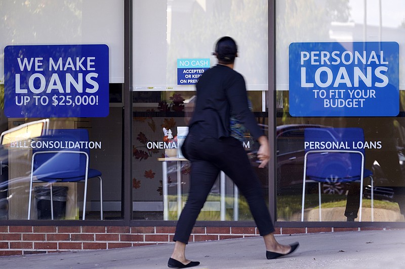 FILE - In this Oct. 1, 2020 file photo, a woman walks past a personal finance loan office in Franklin, Tenn. The rules that dictate how third-party debt collectors interact with consumers are getting an update. These rules say how to apply the more than 40-year-old Fair Debt Collections Practices Act, which serves as a consumer guidebook on dealing with debt collectors. Some changes will help consumers, like one that limits when collections accounts can be reported to a consumer's credit profile. (AP Photo/Mark Humphrey, File)