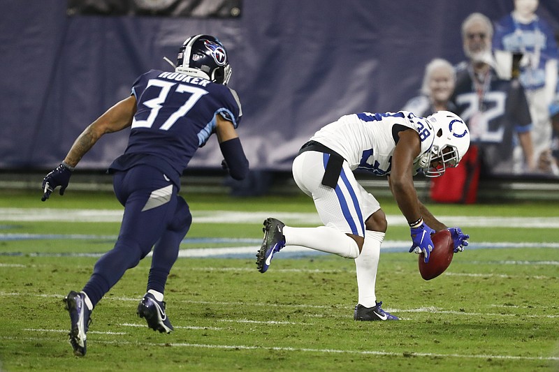 AP photo by Wade Payne / Indianapolis Colts cornerback T.J. Carrie, after teammate E.J. Speed blocked Trevor Daniel's punt, picks up the ball ahead of the Tennessee Titans' Amani Hooker and returns it 6 yards for a touchdown late in the third quarter Thursday night in Nashville. The Colts rallied to beat the Titans 34-17 after trailing by a touchdown three times during the first half.