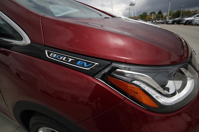 FILE--In this Sunday, May 19, 2019, file photograph, the electric vehicle logo shines off the fender of an unsold 2019 Bolt at a Chevrolet dealership in Englewood, Colo. (AP Photo/David Zalubowski)