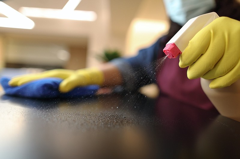 Woman wearing yellow gloves cleaning black countertop cleaning tile clean tile coronavirus mask gloves tile / Getty Images
