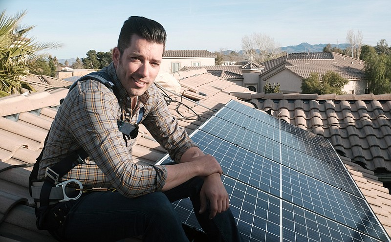 This image released by Independent Lens shows Jonathan Scott from "Property Brothers" installing solar panels on a rooftop in his new documentary "Jonathan Scott's Power Trip." The film premieres Monday night as part of "Independent Lens" on PBS stations across the country. (Neil Berkeley/Independent Lens via AP)