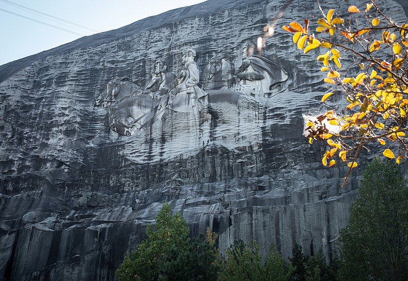 A massive mountainside carving depicting Confederate leaders Jefferson Davis, Robert E. Lee and Stonewall Jackson is shown on Monday, Oct. 5, 2020, in Stone Mountain, Ga. The grassroots group Stone Mountain Action Coalition is seeking to have the Confederate flag removed from the popular park and streets like Robert E. Lee Boulevard renamed there. They also want the park to allow the natural flora and fauna to grow over and obscure the carving. (AP Photo/Ron Harris)