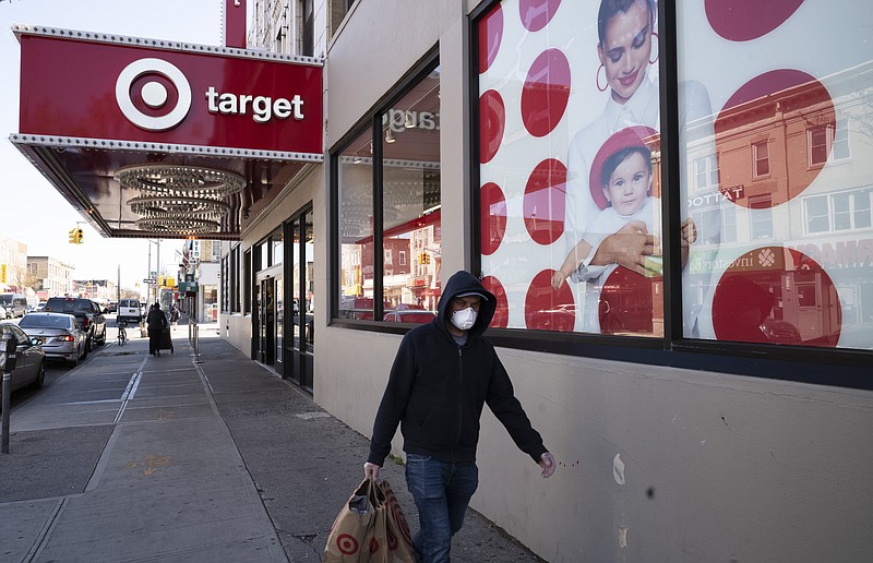 FILE - In this April 6, 2020 file photo, a customer wearing a mask carries his purchases as he leaves a Target store during the coronavirus pandemic, in the Brooklyn borough of New York. Target is the latest big U.S. retailer to show that it's prospering during the pandemic. The Minneapolis company reported Wednesday, Nov. 18 that its online sales surged 155% in the three months that ended Oct. 31. (AP Photo/Mark Lennihan, File)