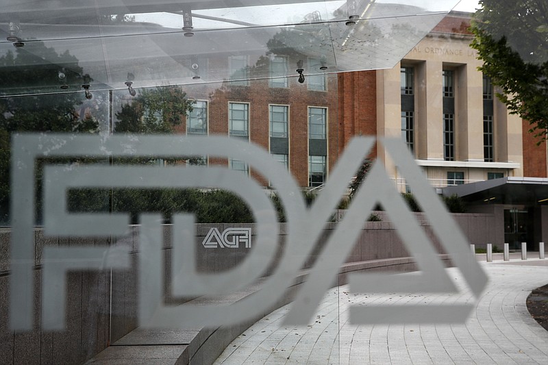 FILE - This Thursday, Aug. 2, 2018, file photo shows the U.S. Food and Drug Administration building behind FDA logos at a bus stop on the agency's campus in Silver Spring, Md. FDA officials on Tuesday, Nov. 17, 2020, allowed emergency use of the first rapid coronavirus test that can be performed and developed entirely at home. (AP Photo/Jacquelyn Martin, File)