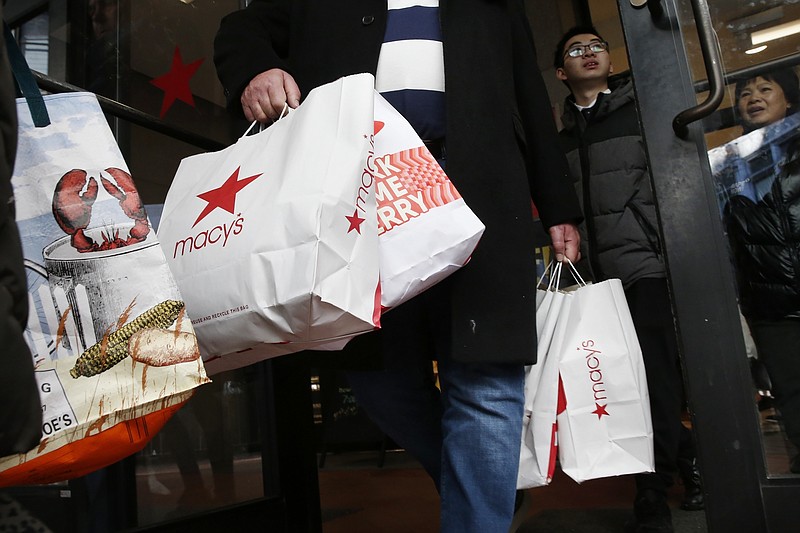 FILE - In this Friday, Nov. 29, 2019 file photo, shoppers leave Macy's in Boston. This year's Black Friday shopping event will be much different from ever before. Retailers will be enforcing social distancing, many stores will be closed on Thanksgiving Day and shoppers will be scooping up deals via their computer screens. (AP Photo/Michael Dwyer, File)