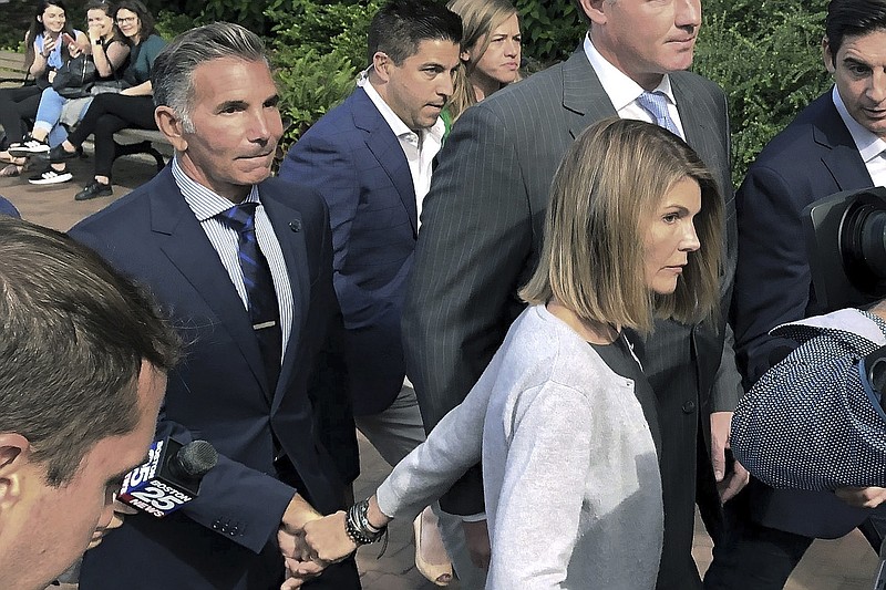 In this Aug. 27, 2019, file photo, Lori Loughlin departs federal court in Boston with her husband, Mossimo Giannulli, left, after a hearing in a nationwide college admissions bribery scandal. Giannulli has reported to prison to begin serving his five-month sentence for bribing his daughters' way into college. Giannulli's wife, "Full House" actor Lori Loughlin, is already behind bars for her role in the college admissions bribery scheme involving prominent parents and elite schools across the country. She began her two-month prison term late last month. (AP Photo/Philip Marcelo, File)