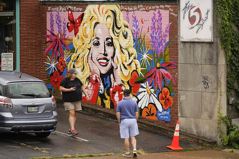 AP Photo by Mark Humphrey/People look at a mural of Dolly Parton outside The 5 Spot, a music club in Nashville, Tenn., in August. Artist Kim Radford said Dolly fans from around the world have contacted her about the mural, which contains a quote from Parton about her support for the Black Lives Matter movement.