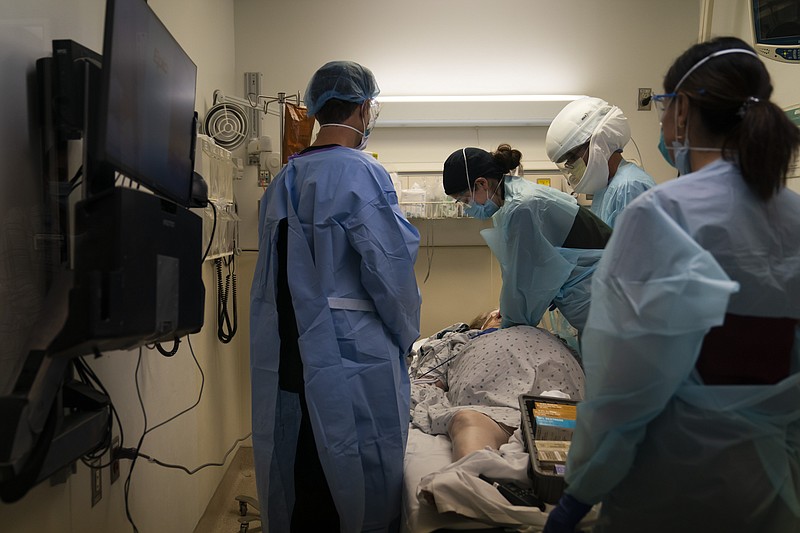 In this Nov. 19, 2020, file photo, EMT Giselle Dorgalli, third from right, performs chest compression on a patient who tested positive for coronavirus in the emergency room at Providence Holy Cross Medical Center in the Mission Hills section of Los Angeles. (AP Photo/Jae C. Hong, File)