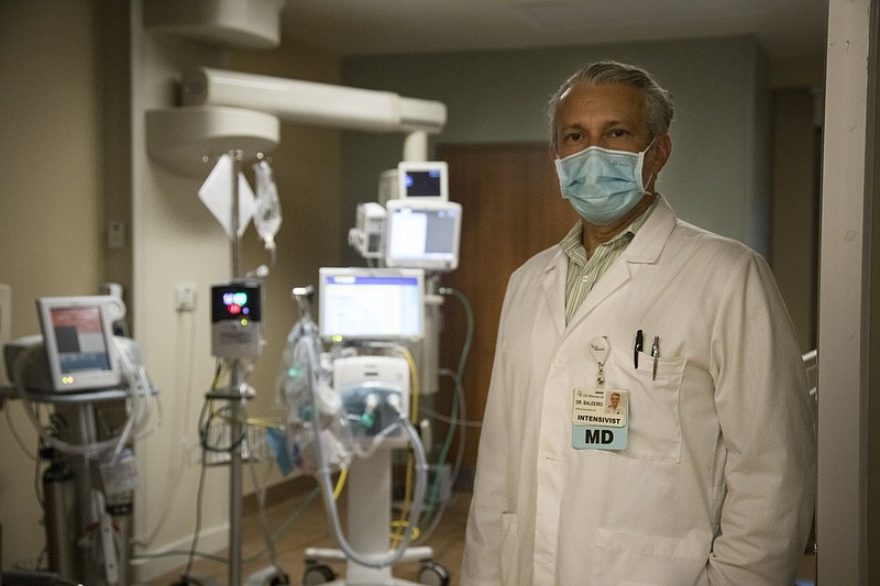 Staff photo by Troy Stolt / Dr. Carlos Baleeiro stands for a portrait in front of machines used to help COVID-19 patients breath in CHI Memorial Hospital's critical care unit in Chattanooga in August. That was the same month that Kaiser Health News and Guardian US tallied 922 health care workers who had died with the illness.