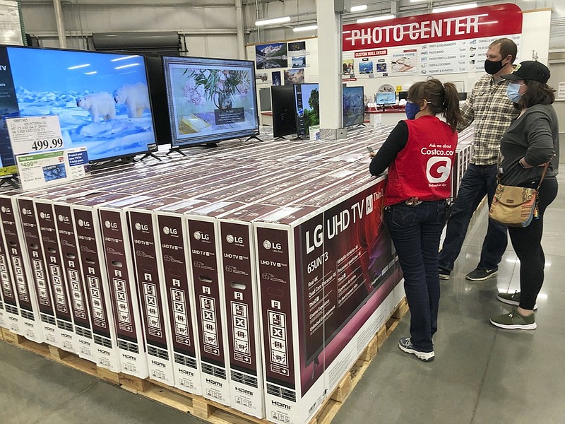 A sales associate helps customers as they consider the purchase of a big-screen television at a Costco warehouse on Wednesday, Nov. 18, 2020, in Sheridan, Colo. U.S. consumer confidence fell to a reading of 96.1 in November as rising coronavirus cases pushed Americans' confidence down to the lowest level since August. The Conference Board said the November reading represented a drop from a revised 101.4 in October. (AP Photo/David Zalubowski)


