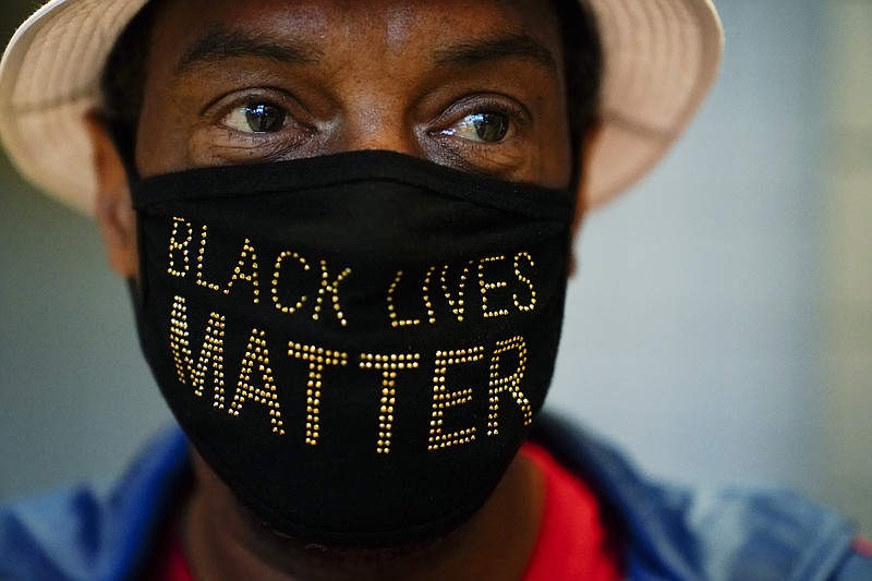 Associated Press File Photo / Calvin Stalling of Atlanta wears his activism on his mask while he waits in line to vote early at the State Farm Arena in October in Atlanta.