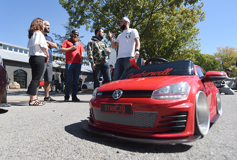Staff photo by Matt Hamilton / Ryan James, right, talks to a group of fellow car enthusiasts as he operates a remote control version of his car.