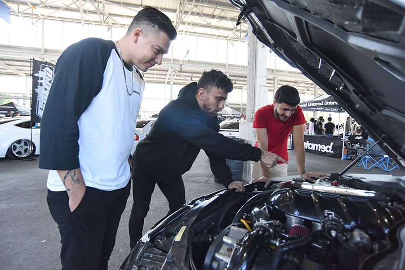 Staff photo by Matt Hamilton / Alec De La Paz, Rammi S. and Khaloo Zaxo examine a car's engine.