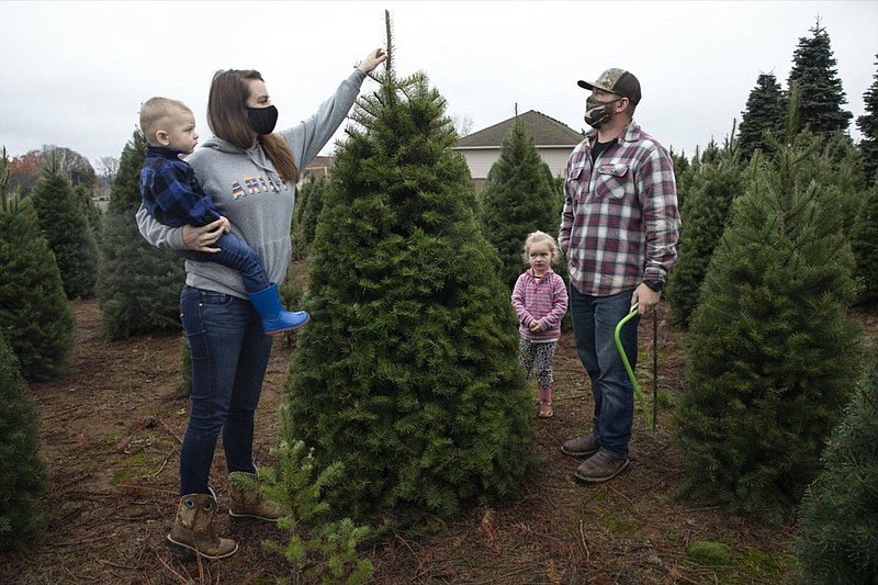 Josh and Jessica Ferrara shop for Christmas trees with son Jayce, 1 year and Jade, 3 years, at Sunnyview Christmas Tree farm on Saturday, Nov. 21, 2020 in Salem, Ore. It's early in the season, but both wholesale tree farmers and small cut-your-own lots are reporting strong demand, with many opening well before Thanksgiving. (AP Photo/Paula Bronstein)


