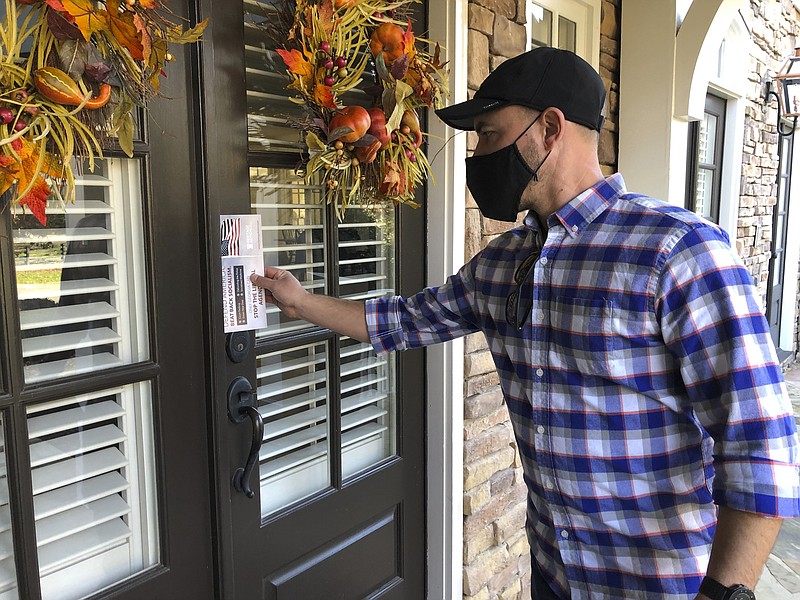 Garrett Bess, vice president of government relations and communications for the conservative activist group Heritage Action For America, leaves information at a residence in a subdivision in Milton, Ga., Friday, Nov. 20, 2020. Bess and a colleague were going door-to-door to encourage people to vote for the conservative candidates in Georgia's Jan. 5 runoff elections for U.S. Senate. The two Georgia races will decide which party controls the Senate, and that has infused voter turnout efforts by the parties and outside groups with new urgency. (AP Photo/Sudhin Thanawala)