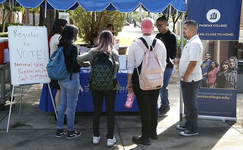 FILE - In this Sept. 24, 2019 file photo students at Phoenix College gather to fill out voter registration forms on National Voter Registration Day on campus, in Phoenix. Immigrant-rights and grassroots organizations that have been mobilizing Latinos in Arizona for nearly two decades helped propel Joe Biden to victory in a traditionally conservative state. (AP Photo/Ross D. Franklin,File)