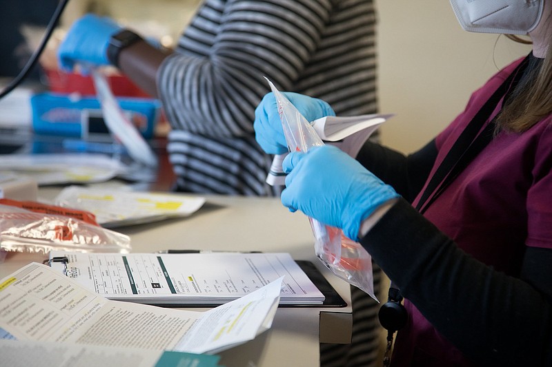 Staff photo by Troy Stolt / Healthcare workers Kristen Pennington, right, and Lisa Bledsoe, left, bag up COVID-19 tests provided by the nonprofit organizations Alleo and CEMPA at Hospice of Chattanooga on Monday, Nov. 30, 2020, in Chattanooga, Tenn.
