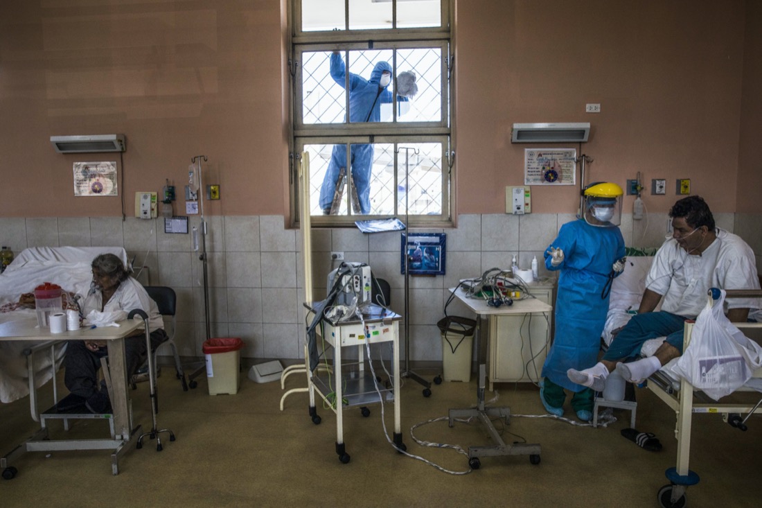 A worker wearing protective gear cleans a window as a nurse tends to a patient inside the intensive care unit for people infected with the coronavirus at the 2 de Mayo Hospital in Lima, Peru, on April 17, 2020. (AP Photo/Rodrigo Abd)
