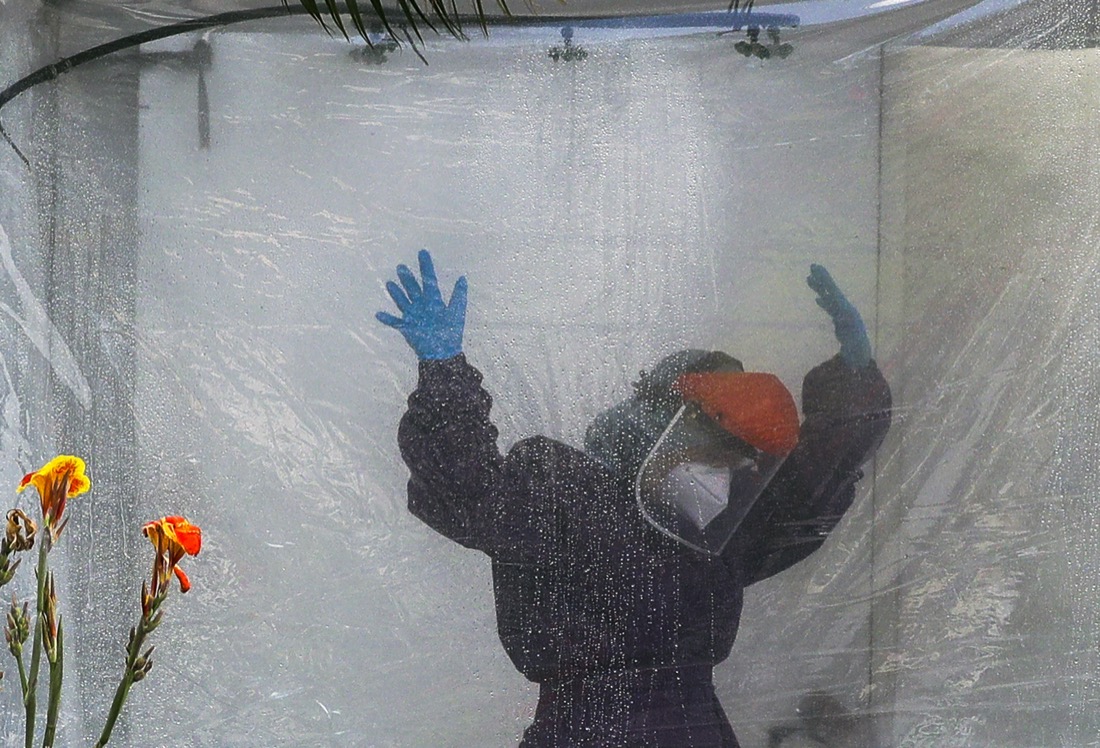 A health worker wearing a protective suit is disinfected in a portable tent outside the Gat Andres Bonifacio Memorial Medical Center in Manila, Philippines, on April 27, 2020, during an enhanced community quarantine to prevent the spread of the coronavirus. (AP Photo/Aaron Favila)