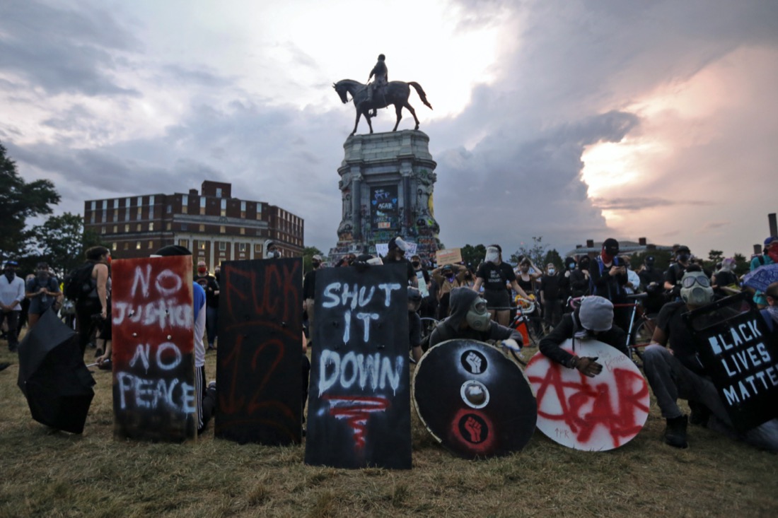 Protesters with shields and gas masks wait for police action as they surround the statue of Confederate Gen. Robert E. Lee on Monument Avenue in Richmond, Va., on June 23, 2020. The state ordered the area around the statue closed from sunset to sunrise, but the protesters had no plans to disperse. (AP Photo/Steve Helber)