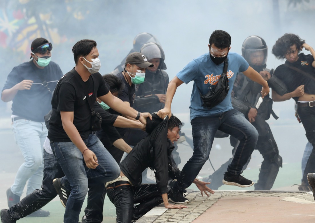 Plainclothes police officers detain demonstrators in Jakarta, Indonesia, on Oct. 8, 2020, during a protest against a new law they say will cripple labor rights and harm the environment. (AP Photo/Tatan Syuflana)