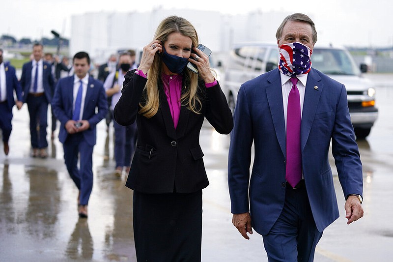 Associated Press File Photo / U.S. Sen. Kelly Loeffler, R-Georgia, left, puts on a face mask as she walks with U.S. Sen. David Perdue, R-Georgia, at UPS Hapeville Airport Hub in Atlanta in July