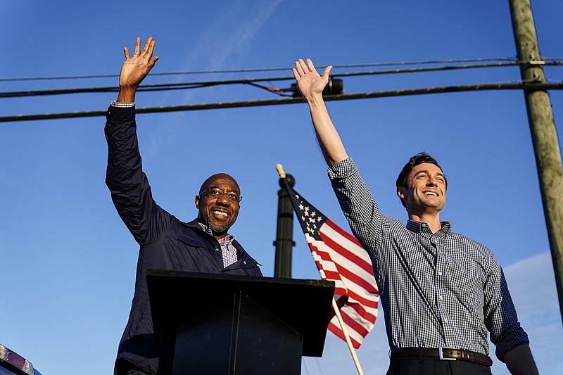 AP file photo by Brynn Anderson/In this Nov. 15, 2020, file photo Georgia Democratic candidates for U.S. Senate Raphael Warnock, left, and Jon Ossoff, right, gesture toward a crowd during a campaign rally in Marietta, Ga.
