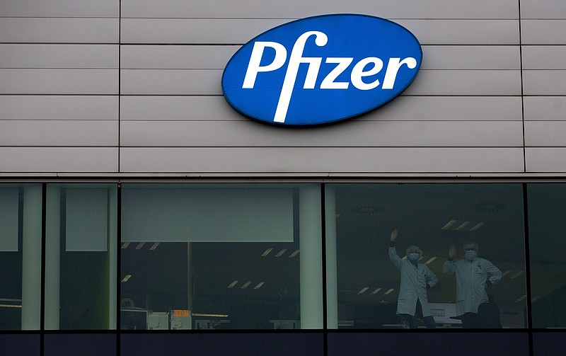 Two workers wave from a window at Pfizer Manufacturing in Puurs, Belgium, on Wednesday, Dec. 2, 2020. British officials authorized a COVID-19 vaccine for emergency use on Wednesday, greenlighting the world's first shot against the virus that's backed by rigorous science and taking a major step toward eventually ending the pandemic. (AP Photo/Virginia Mayo)