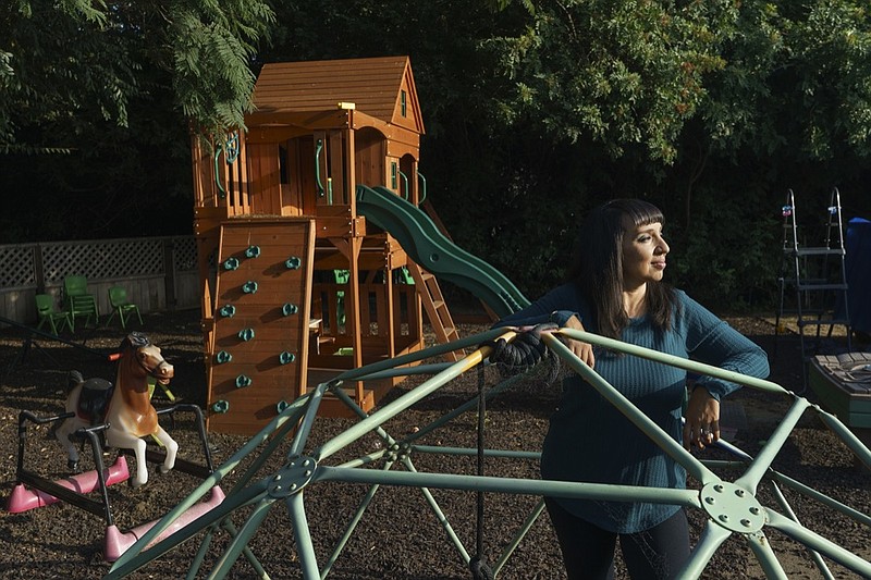 Mary De La Rosa stands inside a play structure in her home backyard, that once housed the now-closed child care program, Creative Explorers, Wednesday, Oct. 21, 2020, in Los Angeles. When De La Rosa closed her toddler and preschool program in March because of the coronavirus pandemic, she fully expected to serve the children again some day. In the end, though, Creative Explorers closed for good. The story of De La Rosa's program is being repeated across the country as the pandemic's effects ripple through child care, disproportionately affecting Black and Latino-owned centers in an industry that has long relied on providers of color. (AP Photo/Damian Dovarganes)