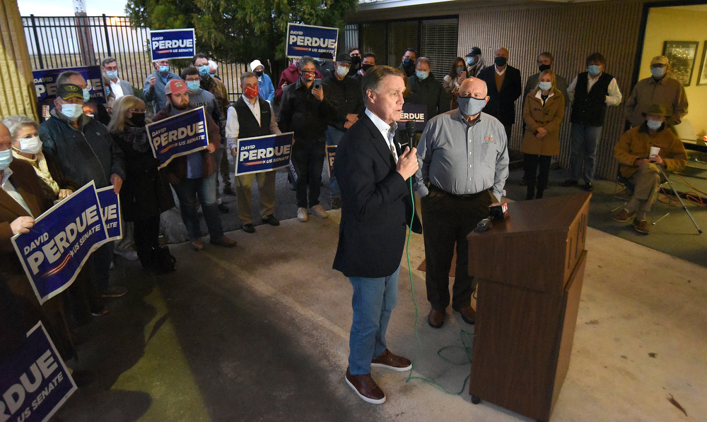 Staff Photo by Matt Hamilton / Sen. David Perdue speaks to a crowd of supporters as former Governor Sonny Perdue looks on at the Dalton Municipal Airport on Monday, Dec. 14, 2020.