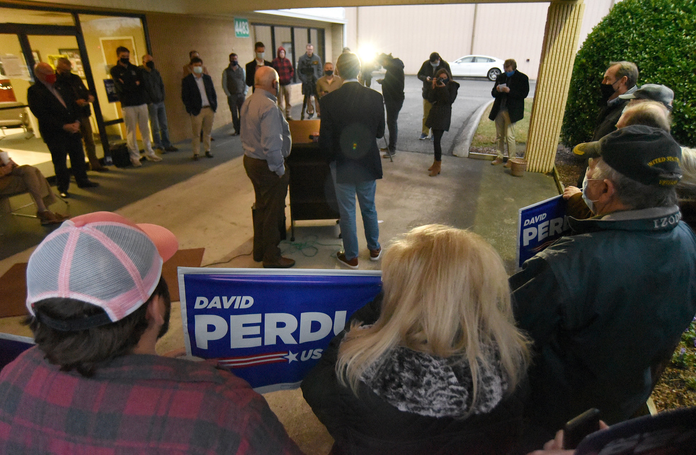 Staff Photo by Matt Hamilton / Supporters gather behind former Governor Sonny Perdue and Sen. David Perdue as they answer questions at the Dalton Municipal Airport on Monday, Dec. 14, 2020.