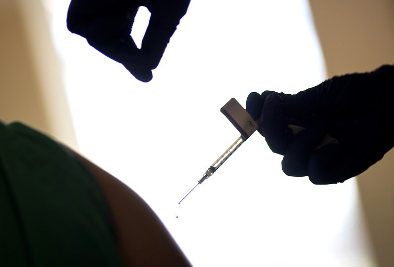 In this Tuesday, Dec. 15, 2020, file photo, a droplet falls from a syringe after a health care worker was injected with the Pfizer-BioNTech COVID-19 vaccine at a hospital in Providence, R.I. The U.S. COVID-19 vaccination campaign has begun, and the few available doses are mostly going into the arms of health care workers and nursing home residents. But what about in January, February and March, when more shots are expected to become available? Who should get those doses? (AP Photo/David Goldman, File)