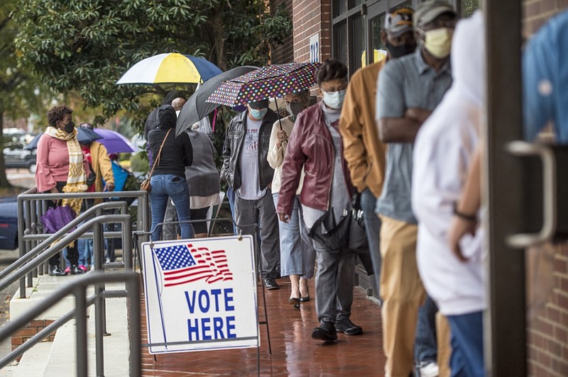 FILE - In this Monday, Dec. 14, 2020, file photo, people wait in line on the first day of advance voting for Georgia's Senate runoff election at the Bell Auditorium in Augusta, Ga. A conservative activist whose organization is challenging the eligibility of thousands of Georgia voters ahead of high-profile U.S. Senate runoffs is claiming a loose alliance with the Georgia Republican Party in what she bills as a widespread election integrity program. (Michael Holahan/The Augusta Chronicle via AP, File)