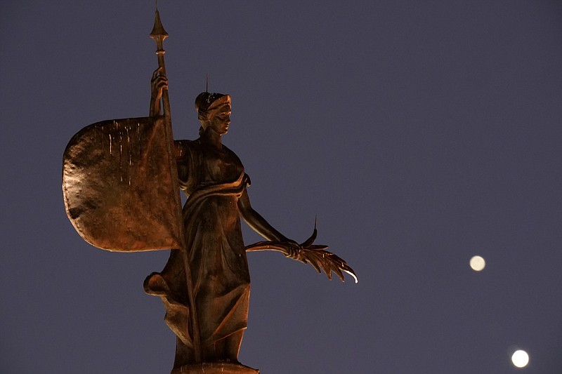 AP Photo by Charlie Riedel/A statue in Kansas City, Missouri, stands in the foreground as Saturn, top, and Jupiter, below, are seen after sunset on Dec. 18. By Monday, the two planets had drawn closer to each other in a "great conjunction" for the first time since the Middle Ages.