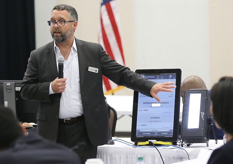 In this Thursday, Aug. 30, 2018 file photo, Eric Coomer from Dominion Voting demonstrates his company's touch screen tablet that includes a paper audit trail at the second meeting of Secretary of State Brian Kemp's Secure, Accessible & Fair Elections Commission in Grovetown, Ga. Eric Coomer, driven into hiding by death threats has filed a defamation lawsuit against President Donald Trump's campaign, two of its lawyers and some conservative media figures and outlets, Tuesday, Dec. 22, 2020. (Bob Andres/Atlanta Journal-Constitution via AP, File)