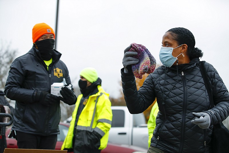 Election Defender volunteers hand out knitted hats to voters, including one at right, during early voting for the Senate runoff election at Ron Anderson Recreation Center, Thursday, Dec. 17, 2020, in Powder Springs, Ga. (AP Photo/Todd Kirkland)